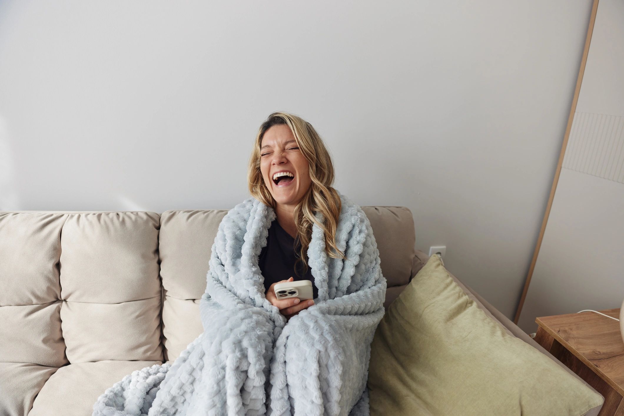 Happy customer relaxing with a cozy blanket on a couch